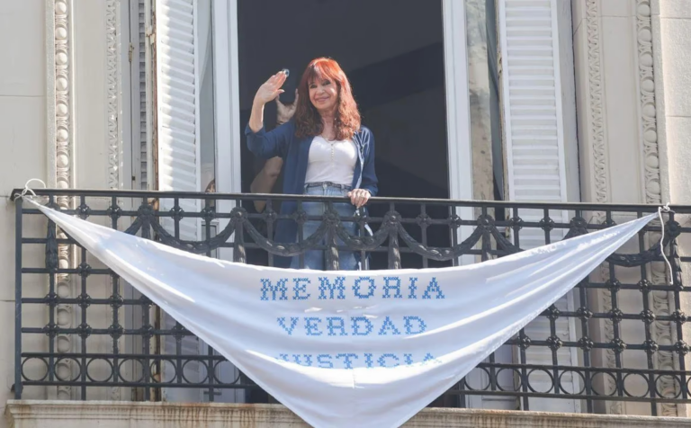 Cristina Fernández en el balcón de su departamento con una bandera que dice 'Memoria, Verdad y Justicia'.