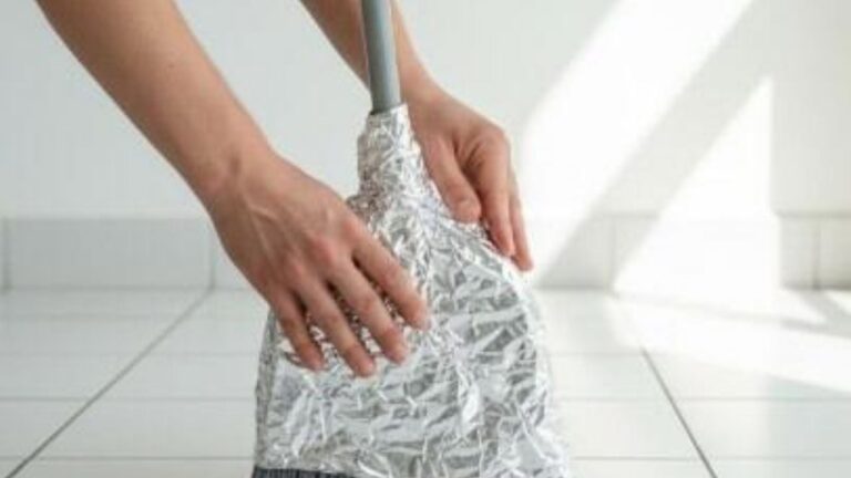 Escoba con papel aluminio en sus cerdas, lista para barrer el piso de un hogar.