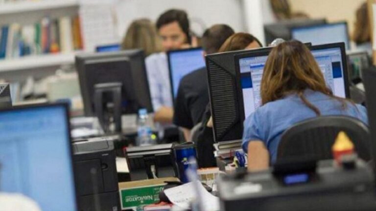 Personas trabajando en oficinas con múltiples pantallas, representando el pluriempleo