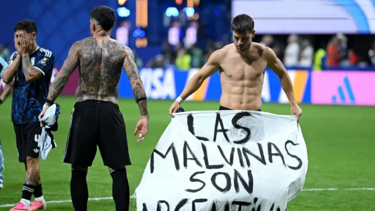 Futbolistas argentinos celebrando con una bandera que dice Las Malvinas son argentinas en un estadio de Atlanta