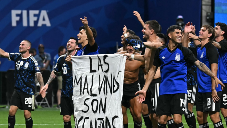 Jugadores de la Selección Argentina celebran con una bandera que dice Las Malvinas son argentinas