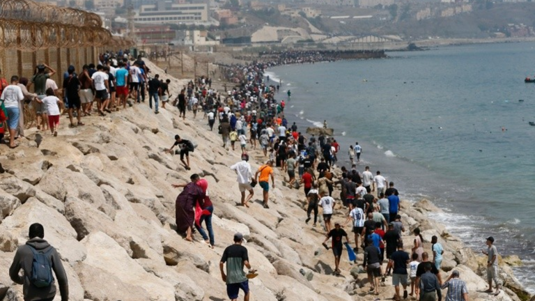 Multitud de personas corriendo hacia la frontera entre Marruecos y Ceuta