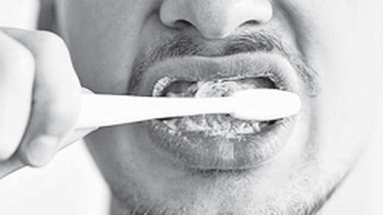 Persona cepillándose los dientes en el baño por la mañana