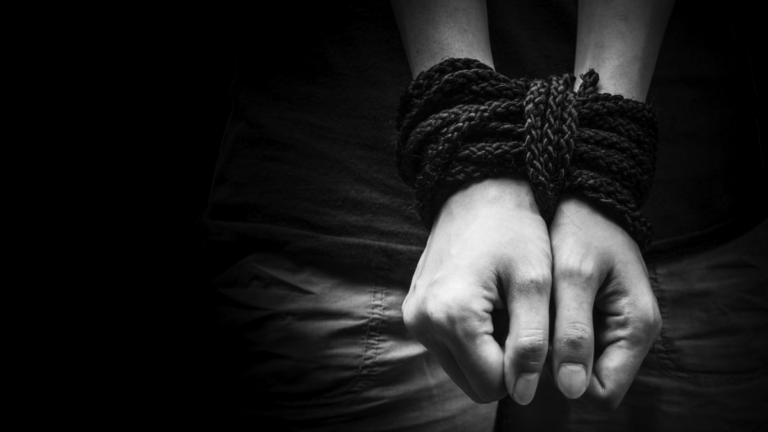 Ilustración de una persona frente a una pantalla con cadenas digitales, simbolizando la trata de personas en entornos virtuales