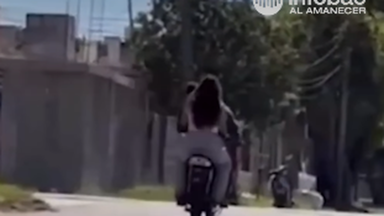 Captura del video de la pareja en moto realizando un willy con un bebé en brazos